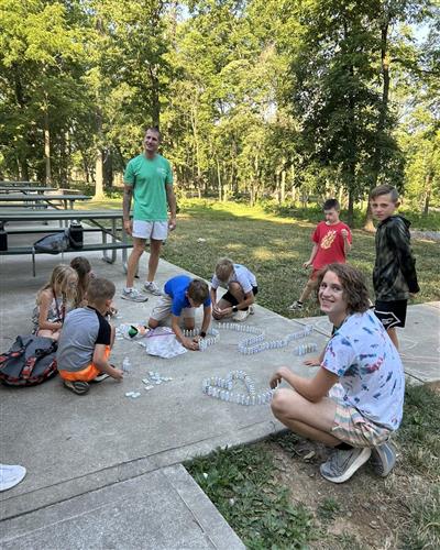 Campers and counselors building a domino train.